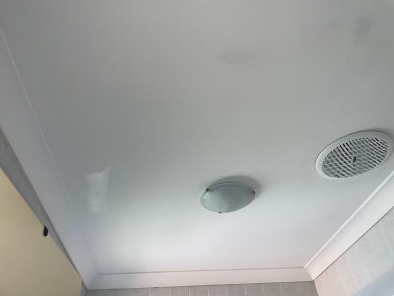 White ceiling with a light fixture and a vent.