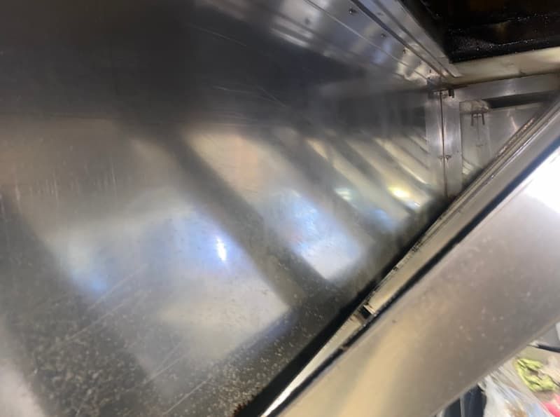 Shiny metal interior, likely a vehicle or appliance. Light reflects across the surface.