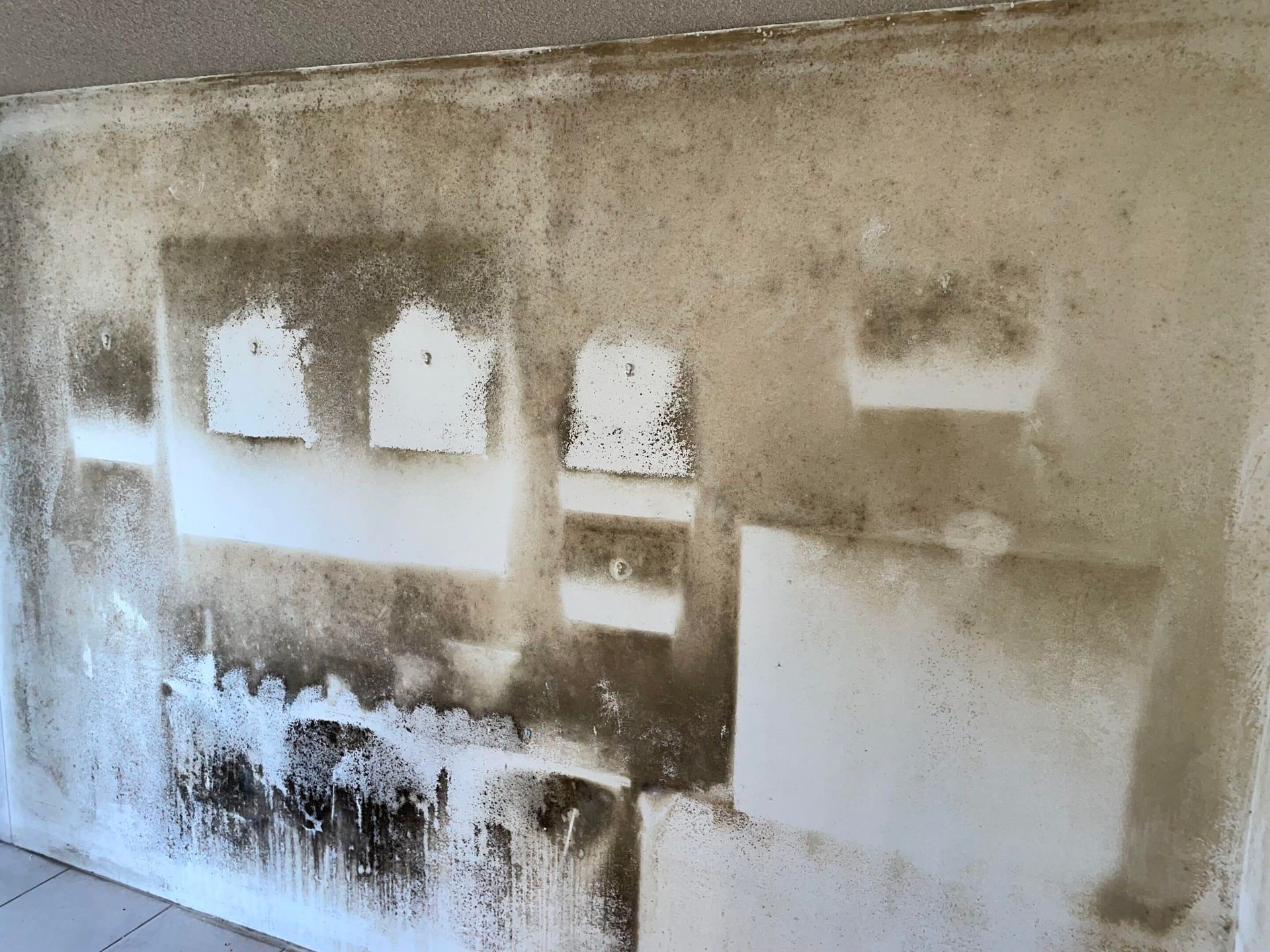 Wall with dark staining and light-colored squares, possibly mold or water damage.