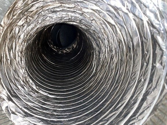 View inside a flexible, metallic air duct. The interior coils inwards, dark at the center.