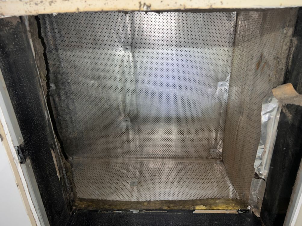 Inside view of a rectangular duct, showing a perforated metal screen and duct insulation.