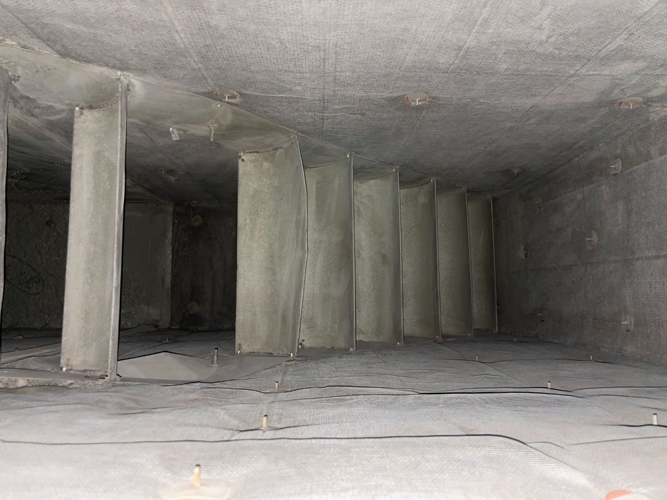 Interior of a large, gray concrete chamber with several columns, dimly lit.