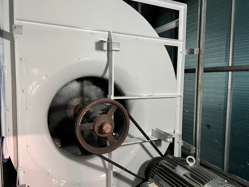 Large white industrial blower with a black belt connecting to a motor.