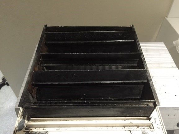 Black, rectangular louvered vent with horizontal slats, viewed from below.