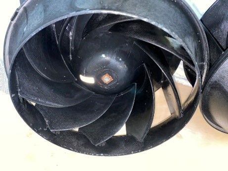 Black impeller fan with curved blades inside a dark housing.