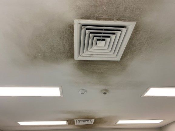 Ceiling with dark staining around air vents and lights, indicating potential water damage or mold.