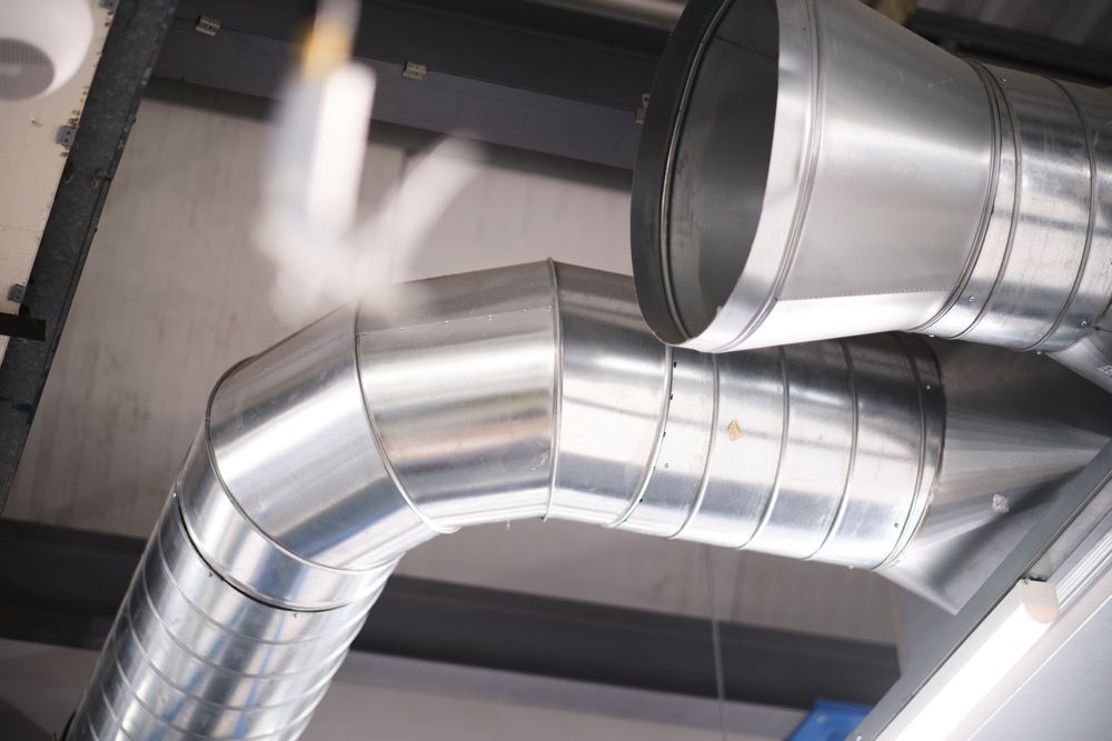Metal ventilation ducts on a ceiling, with vapor escaping from a joint.