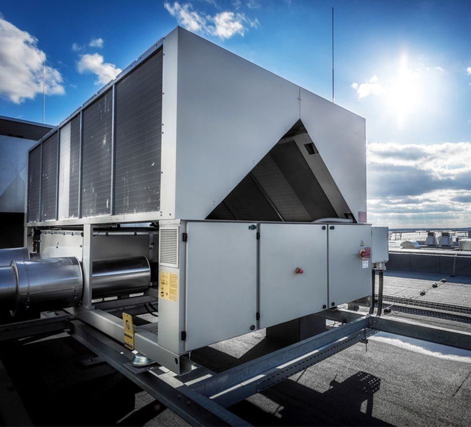 HVAC unit on a rooftop under a bright sunny sky. Metal and gray in color.