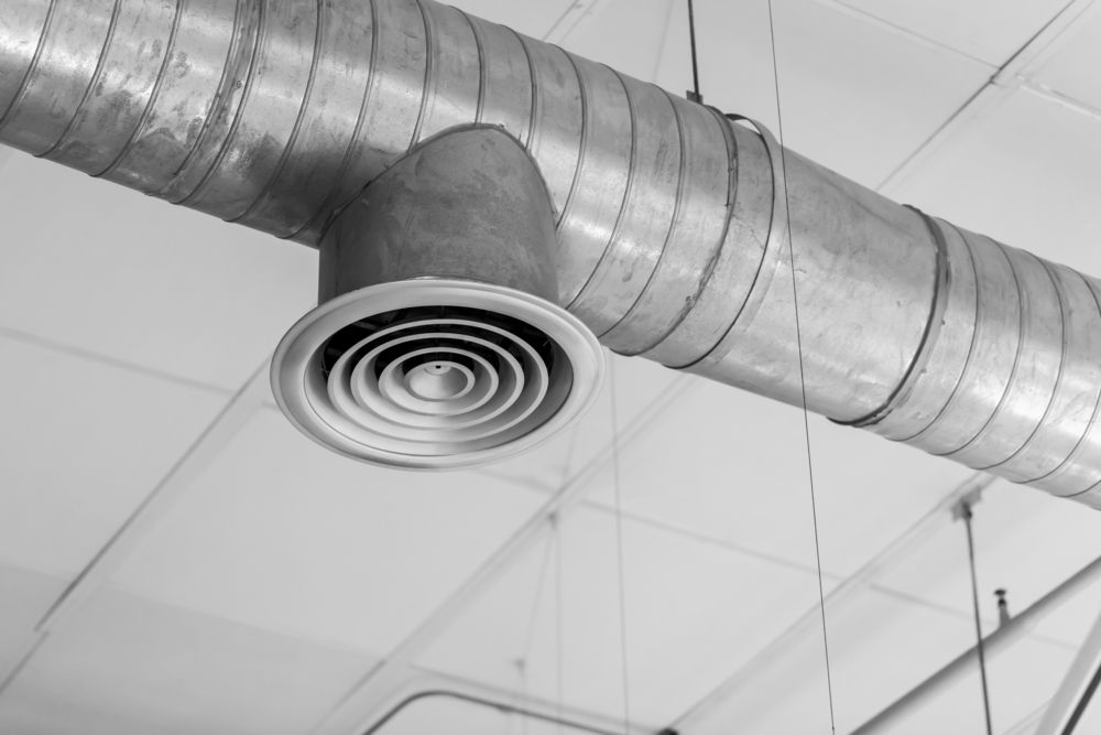 Air vent attached to a metal duct suspended from a ceiling.