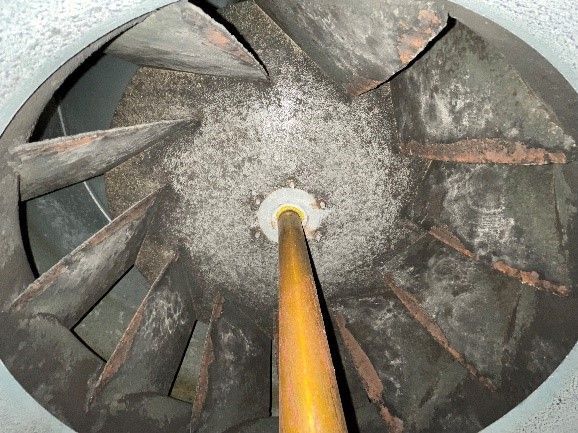 Inside of a dirty HVAC blower fan, showing dust and rust. A yellow tube is in the center.