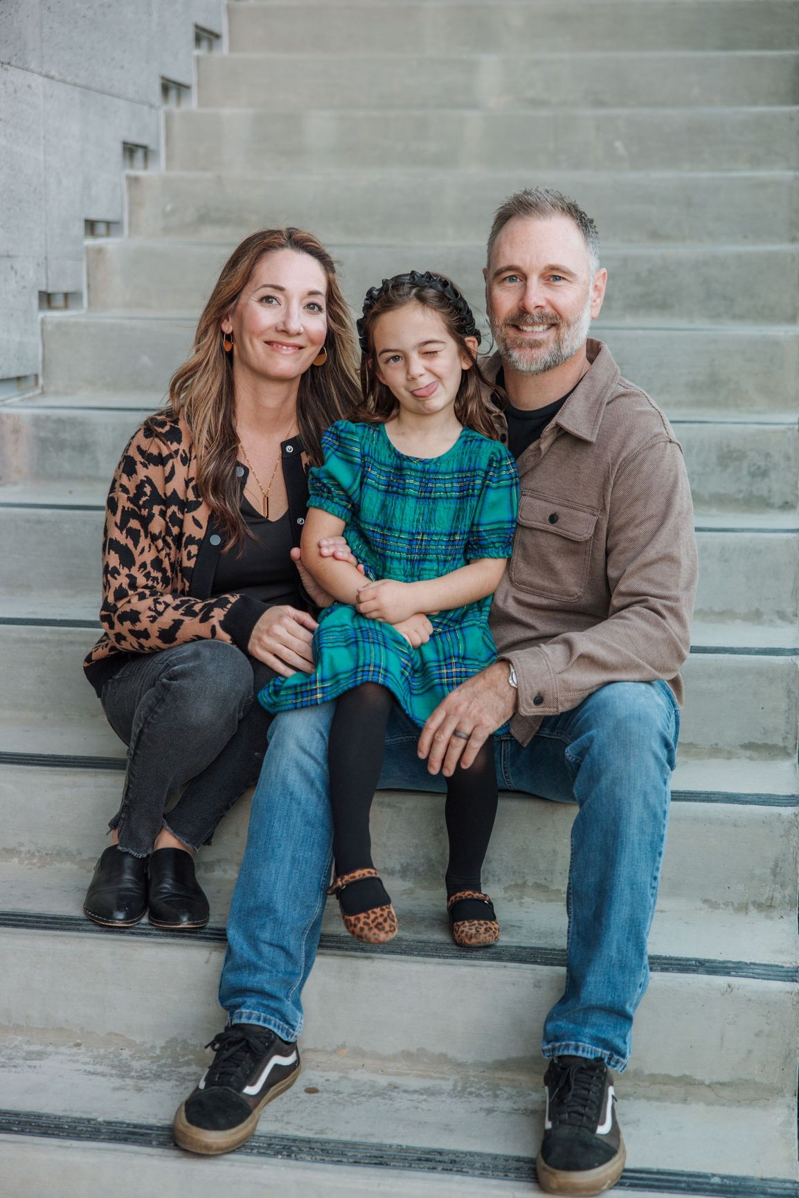 Family seated on concrete steps, smiling at the camera indoors.