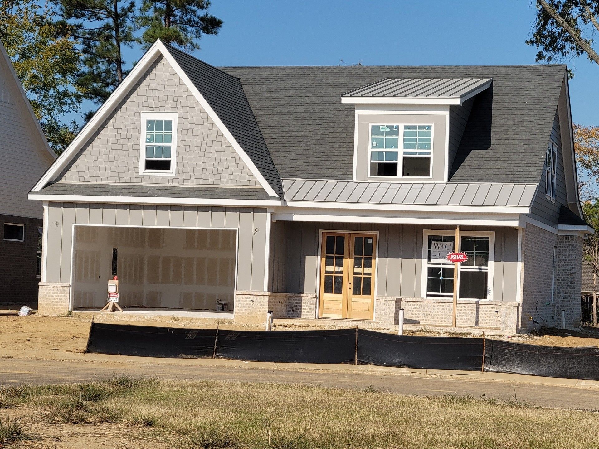 New house under construction with gray siding and a garage.