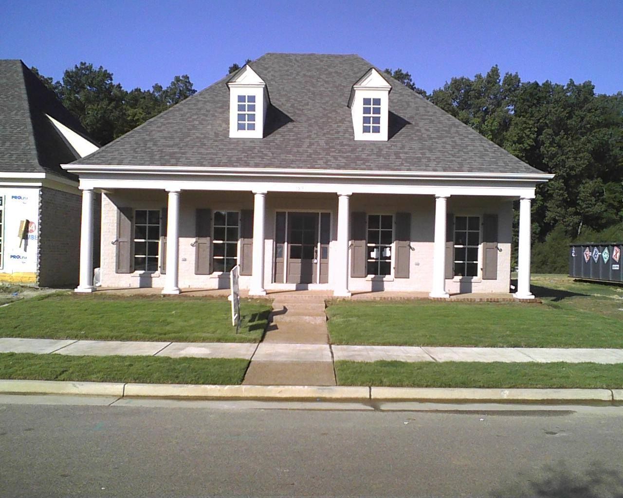 House with white columns, gray roof, two dormers, front yard, and a sidewalk.
