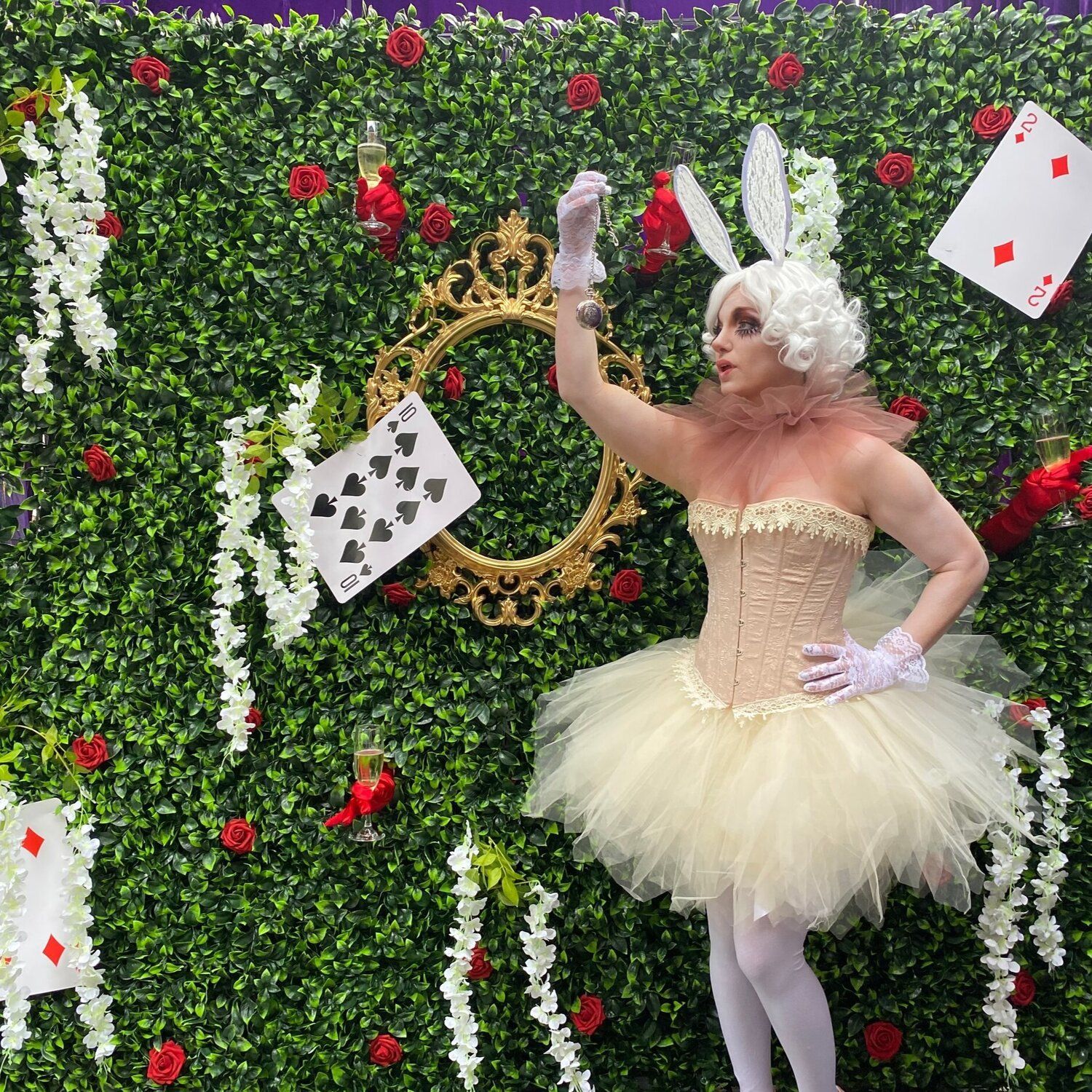 A woman in a bunny costume is standing in front of a green wall.