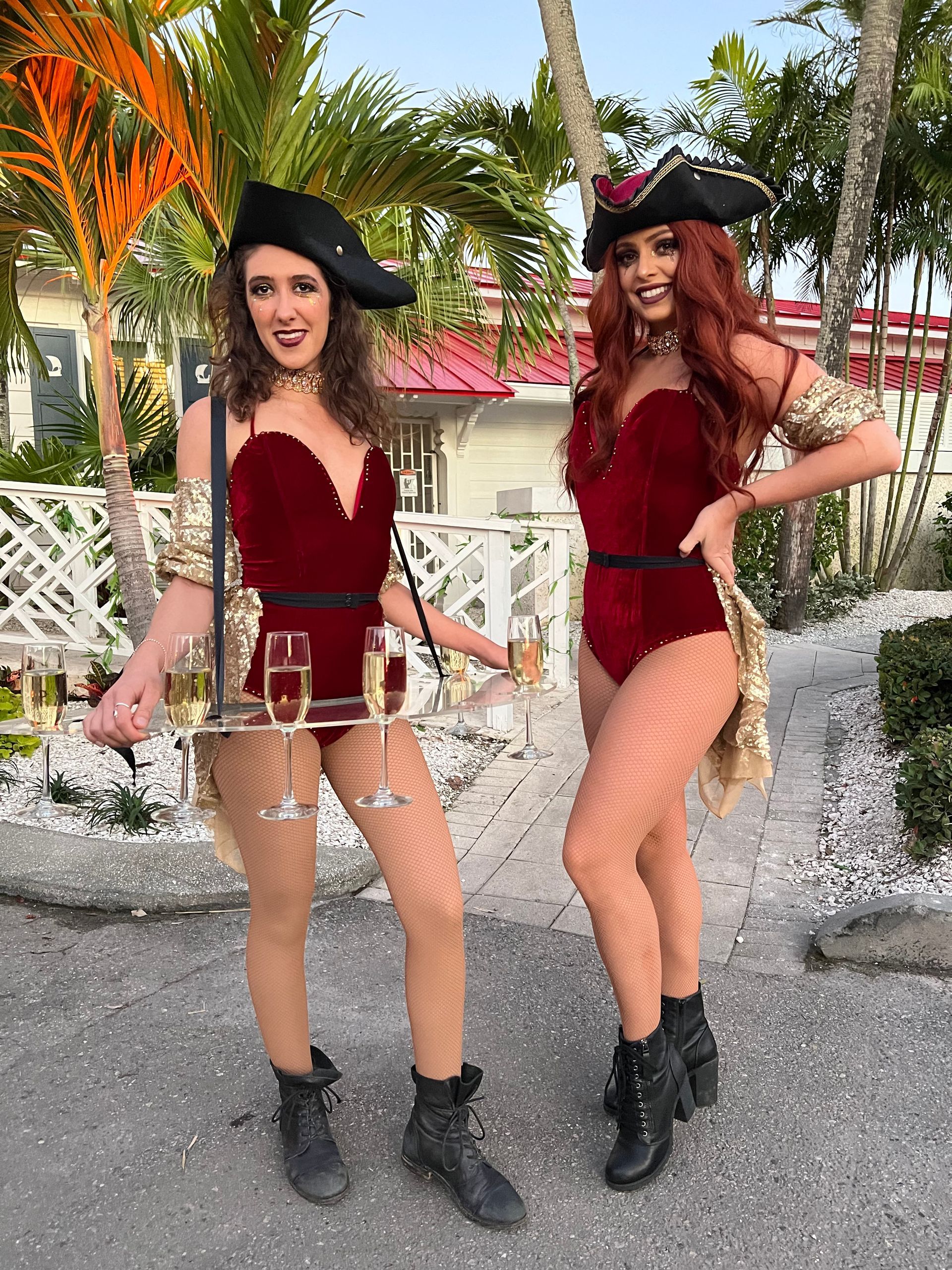 Two women in pirate costumes are standing next to each other holding champagne glasses.