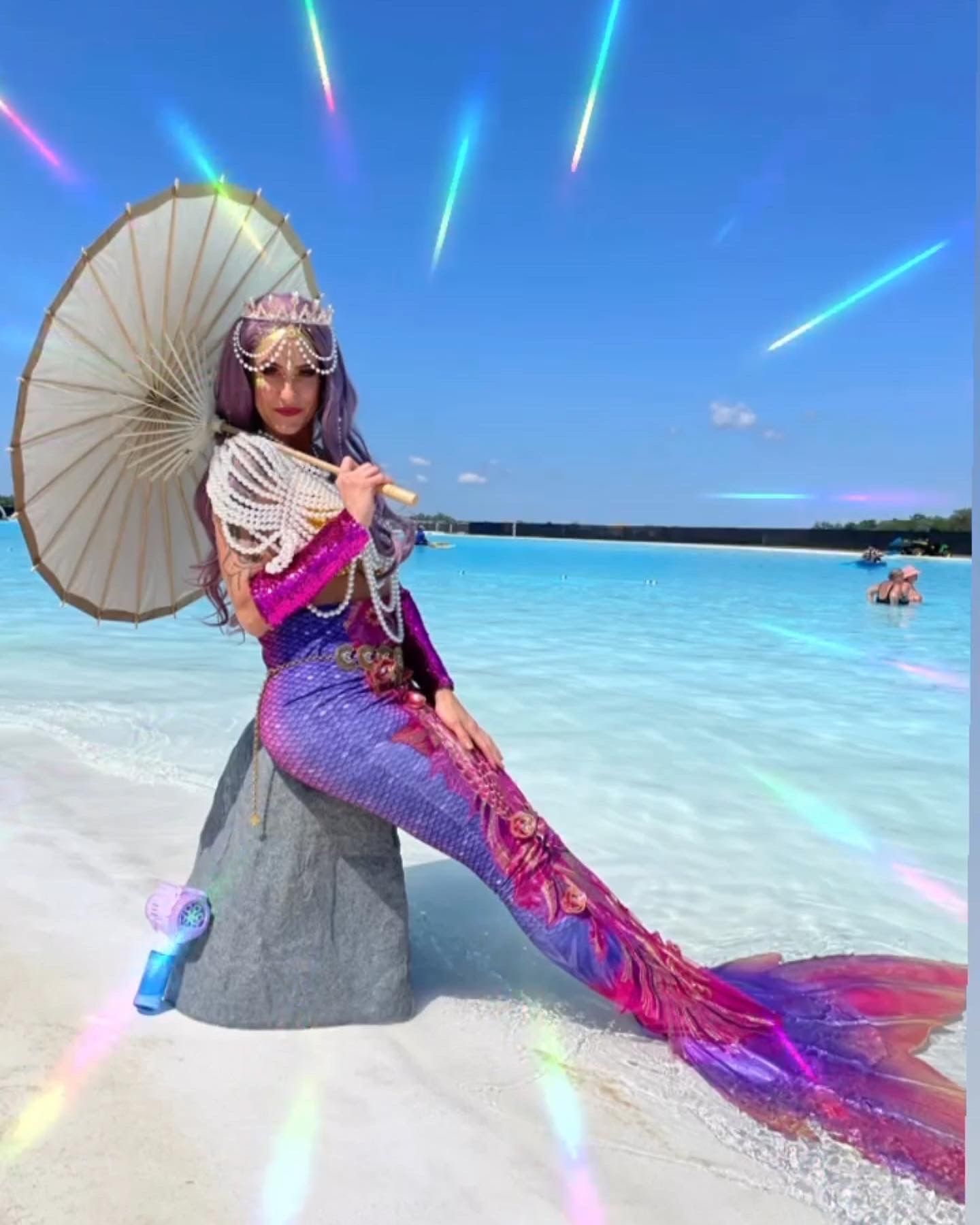 A woman dressed as a mermaid is sitting on the edge of a pool.