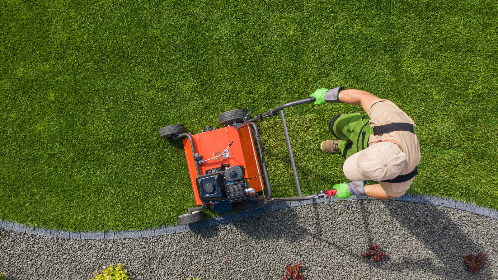 An aerial view of a man using a lawn mower to cut the grass.