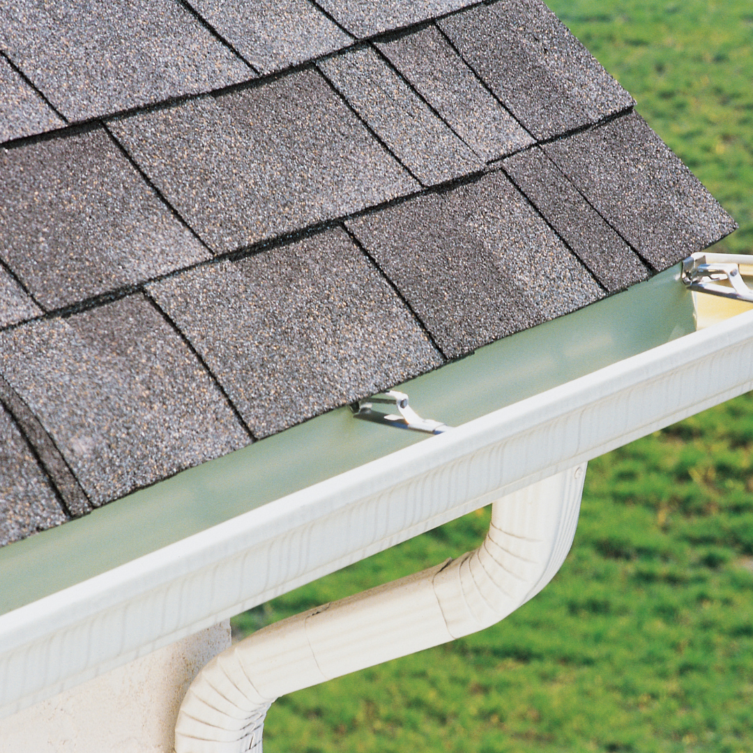 A close up of a gutter with a roof in the background
