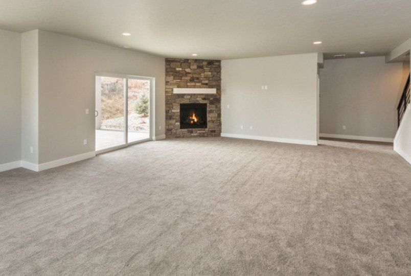 Spacious empty living room with carpet, fireplace, sliding glass door, and recessed lighting.