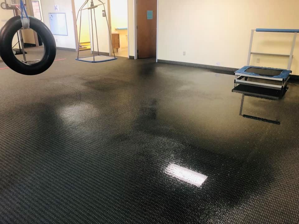 Gym room with black rubber flooring, a hanging tire, and metal equipment racks along the wall