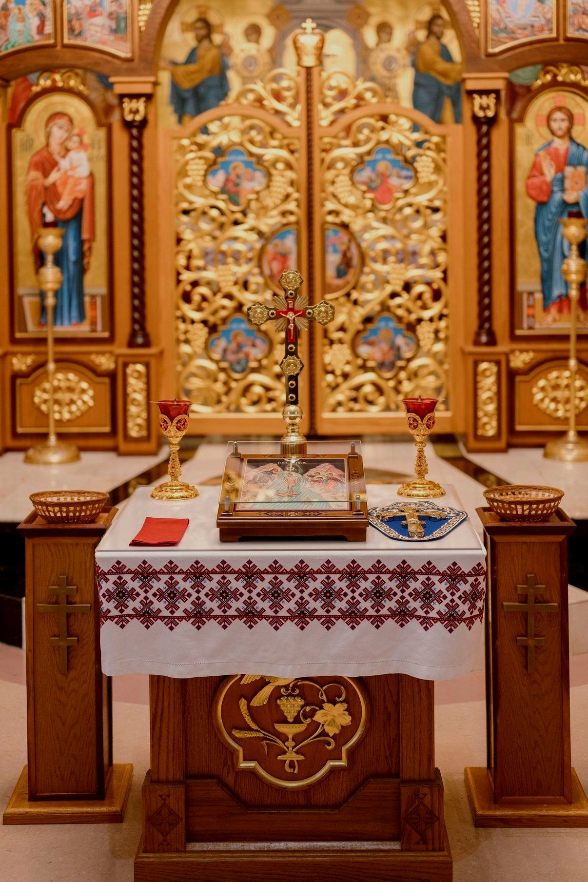 Ornate church altar with gold iconostasis, candles, and embroidered altar cloth
