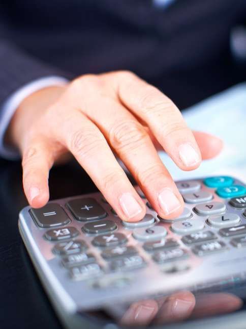 Hand pressing calculator keys on a desk