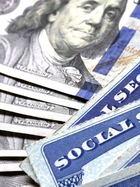 Stack of U.S. Social Security cards and a $100 bill close-up