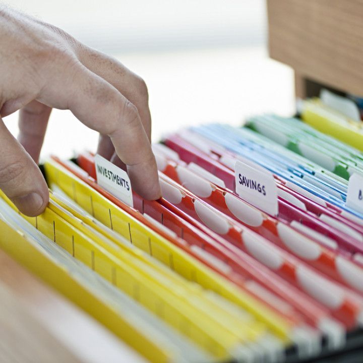 Hand placing a tabbed file in a colorful file organizer drawer