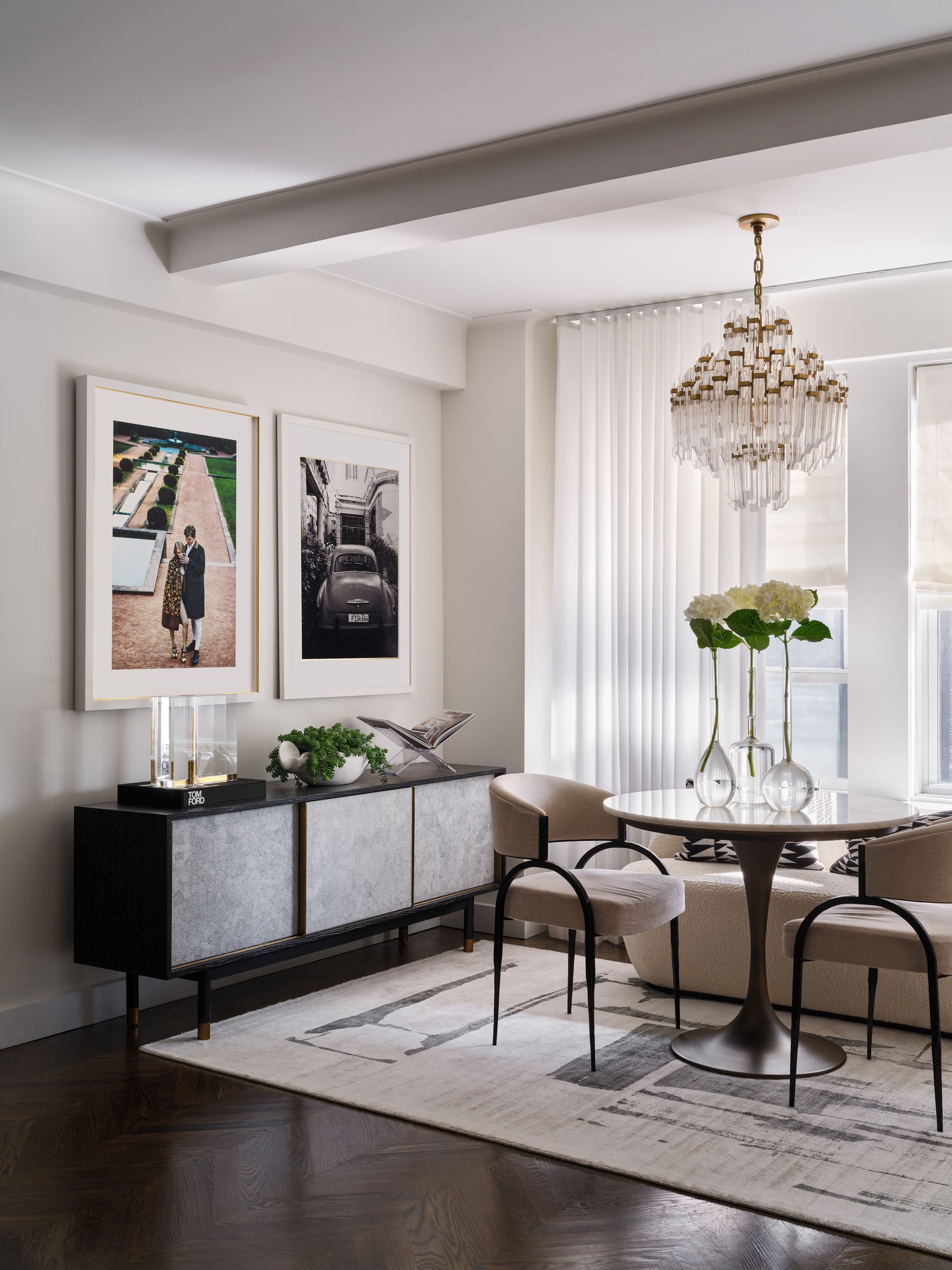 Elegant dining room with chandelier, round table, upholstered chairs, and framed wall art