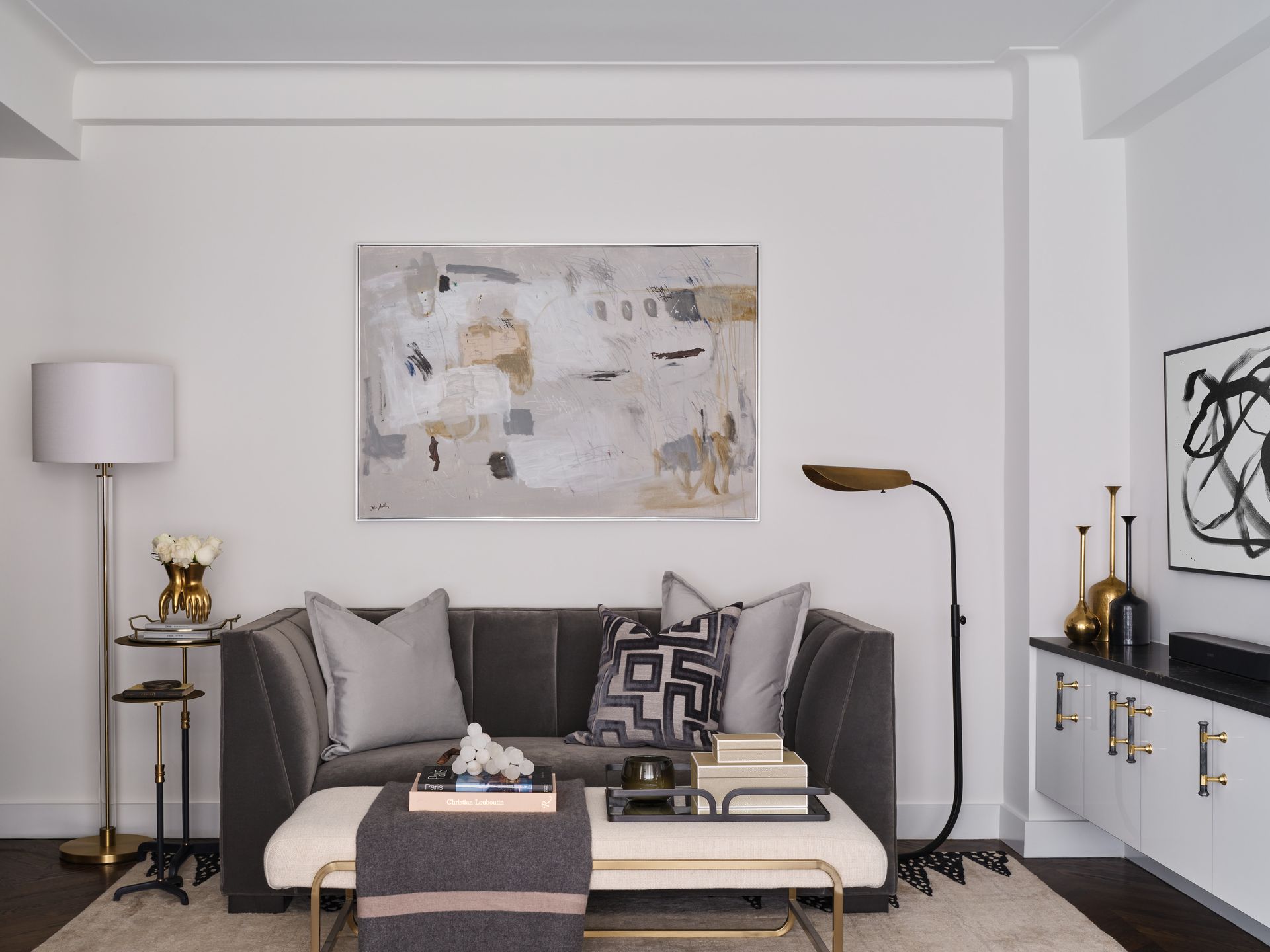 Modern living room with gray sofa, abstract wall art, floor lamp, and black-and-white decor