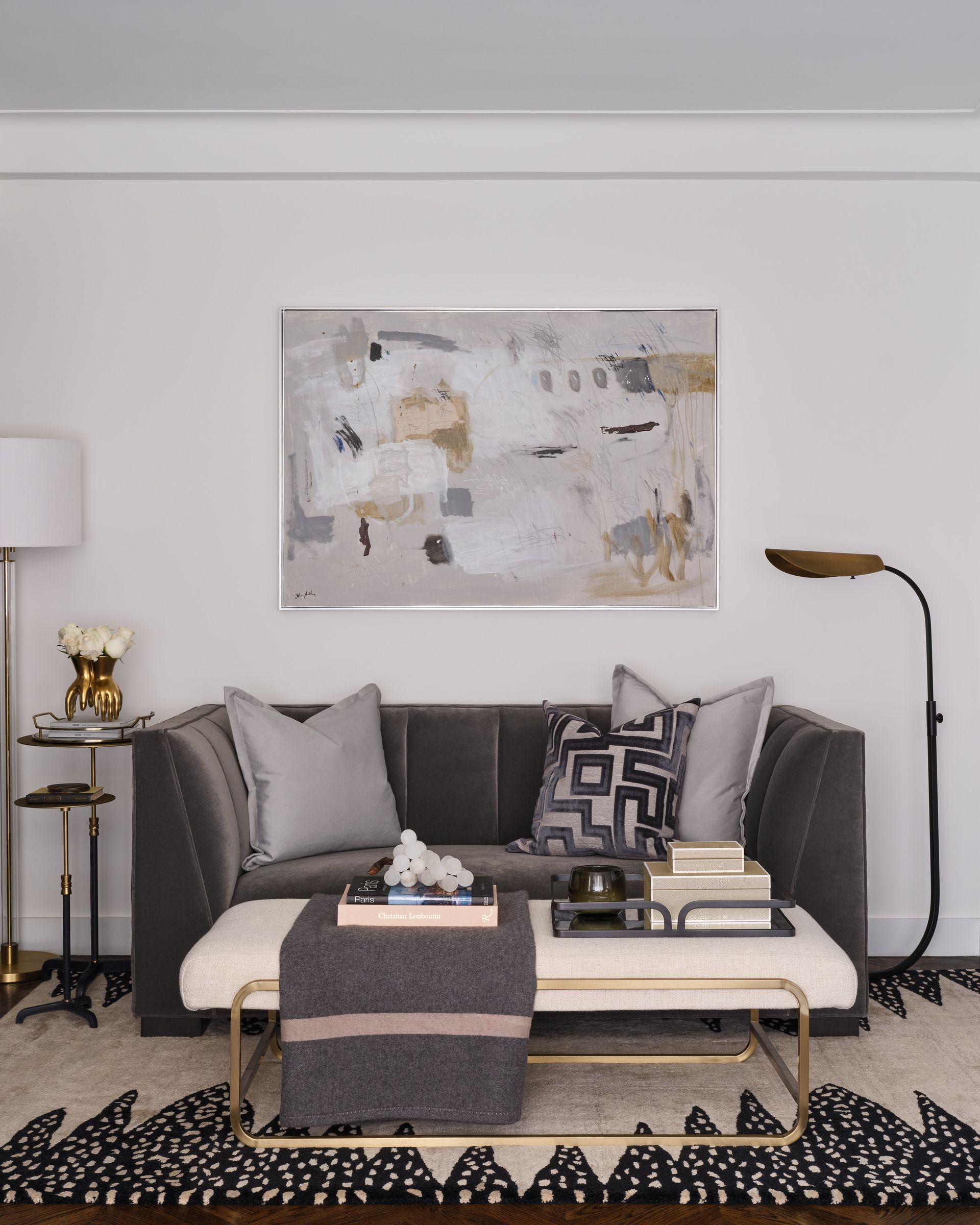 Modern living room with gray sofa, abstract wall art, floor lamp, and patterned rug