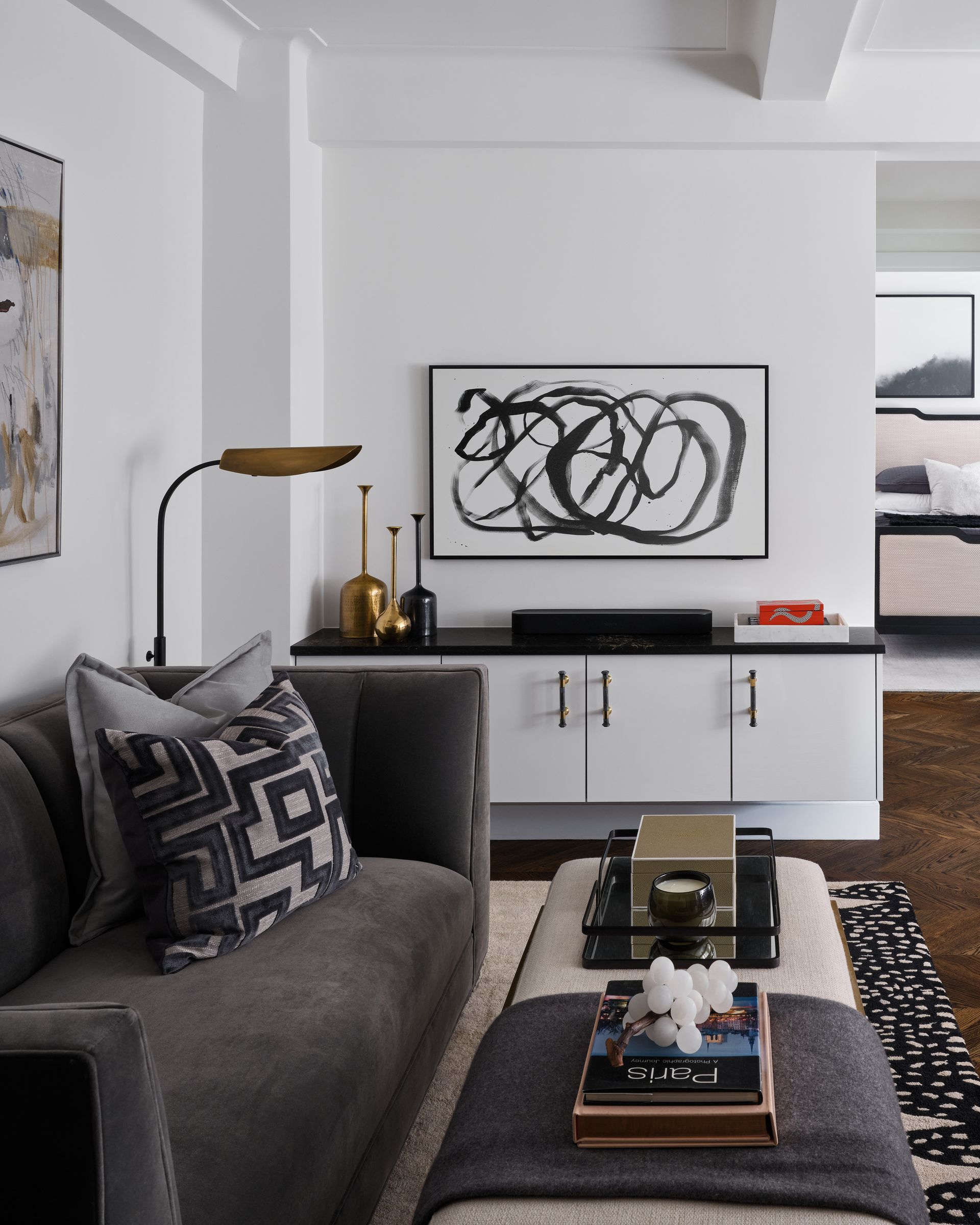 Modern living room with gray sofa, abstract wall art, white console, and floor lamp