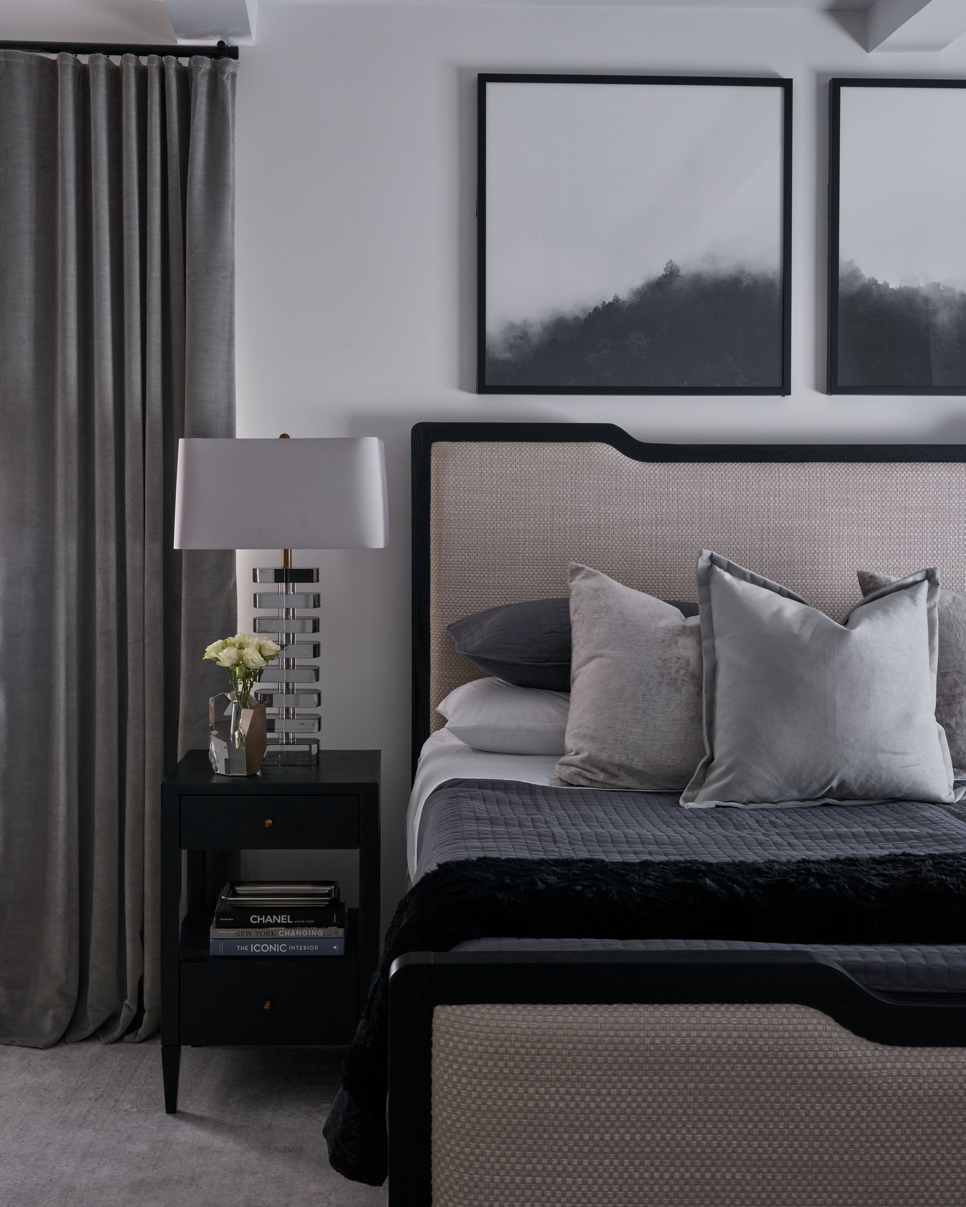 Modern bedroom with gray curtains, upholstered bed, bedside lamp, and framed wall art