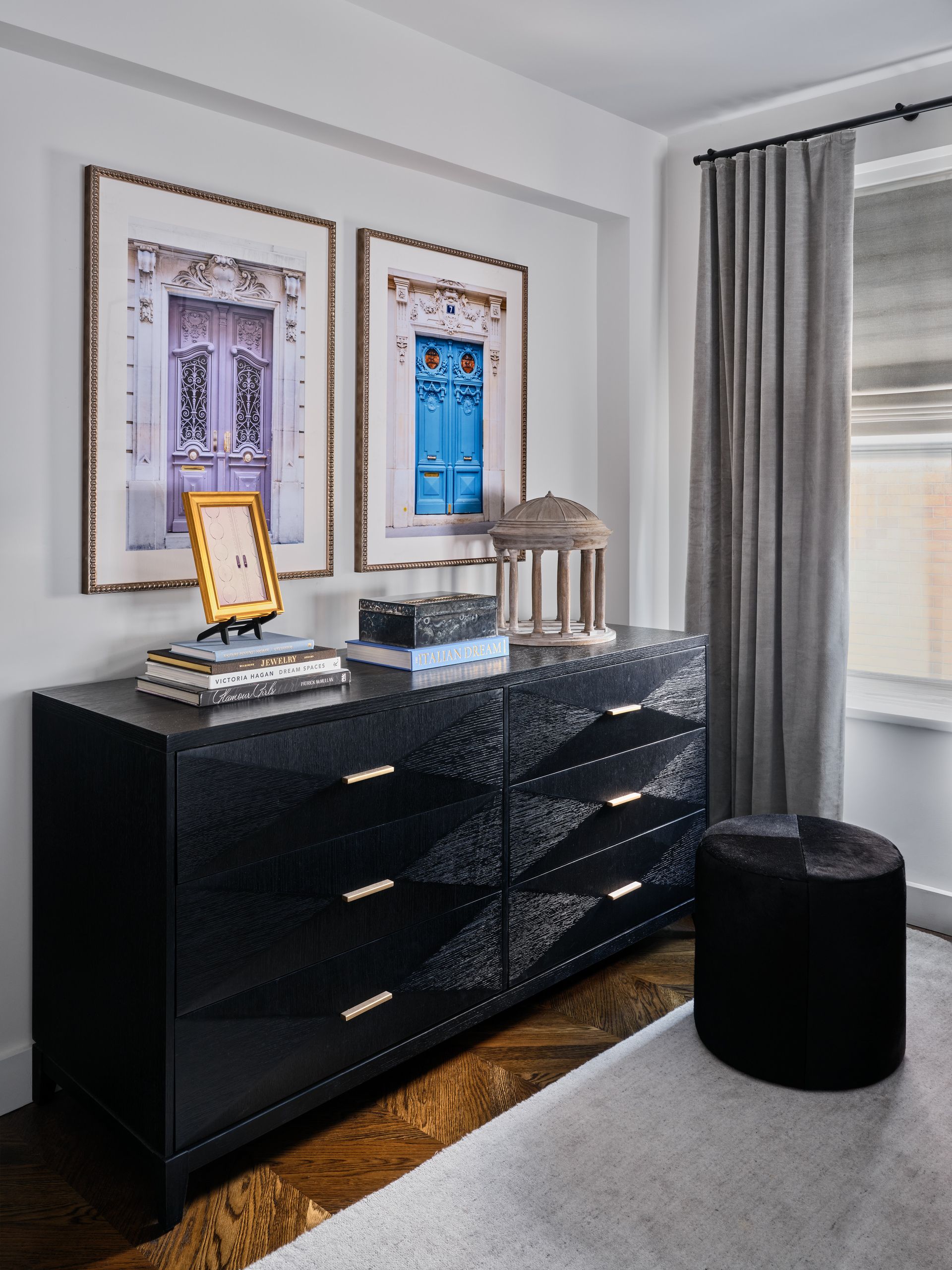 Modern black dresser with decor in a bright bedroom beside a window and gray curtains