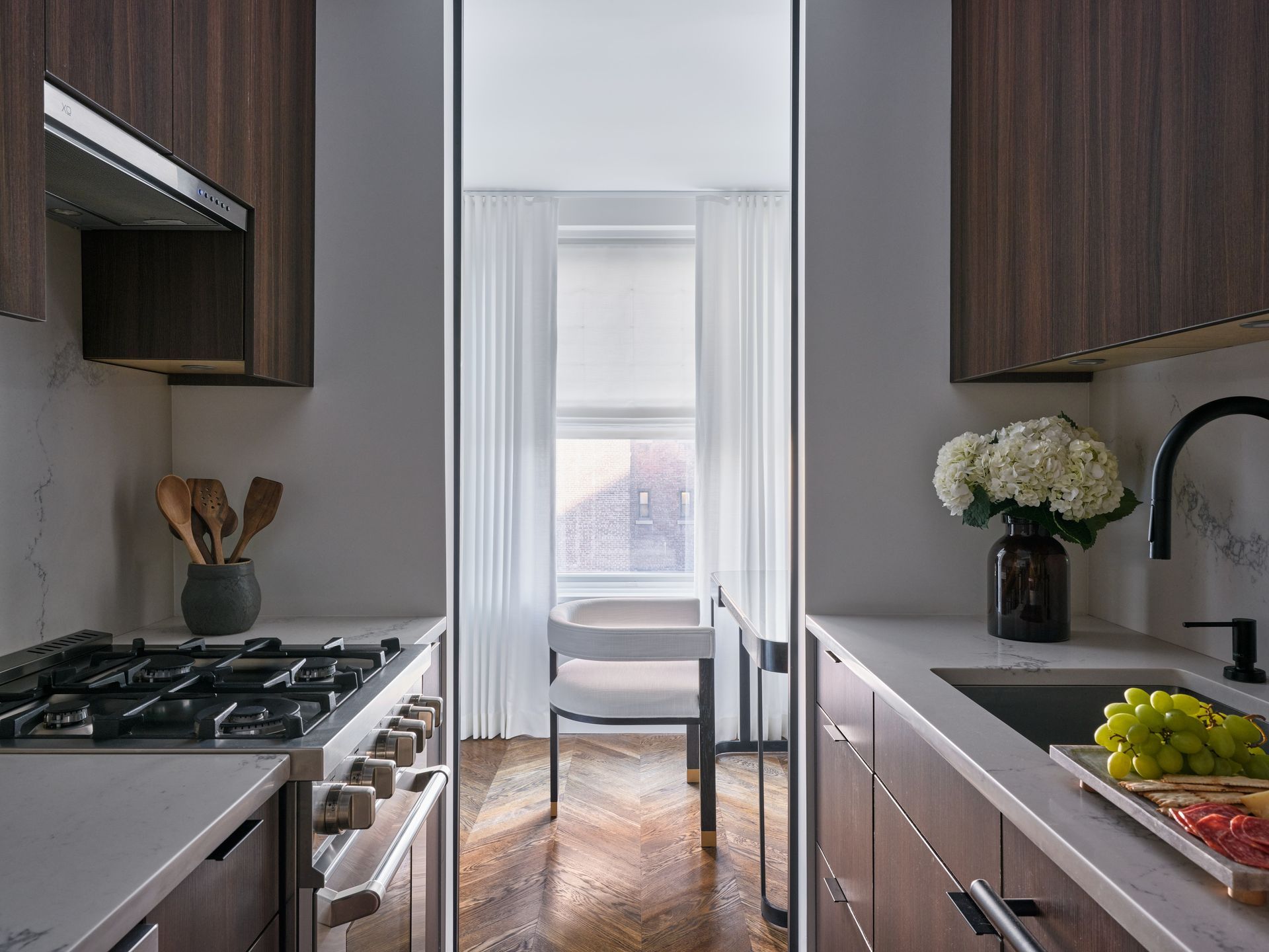 Modern kitchen with dark cabinets, gray counters, and a dining nook by a bright window