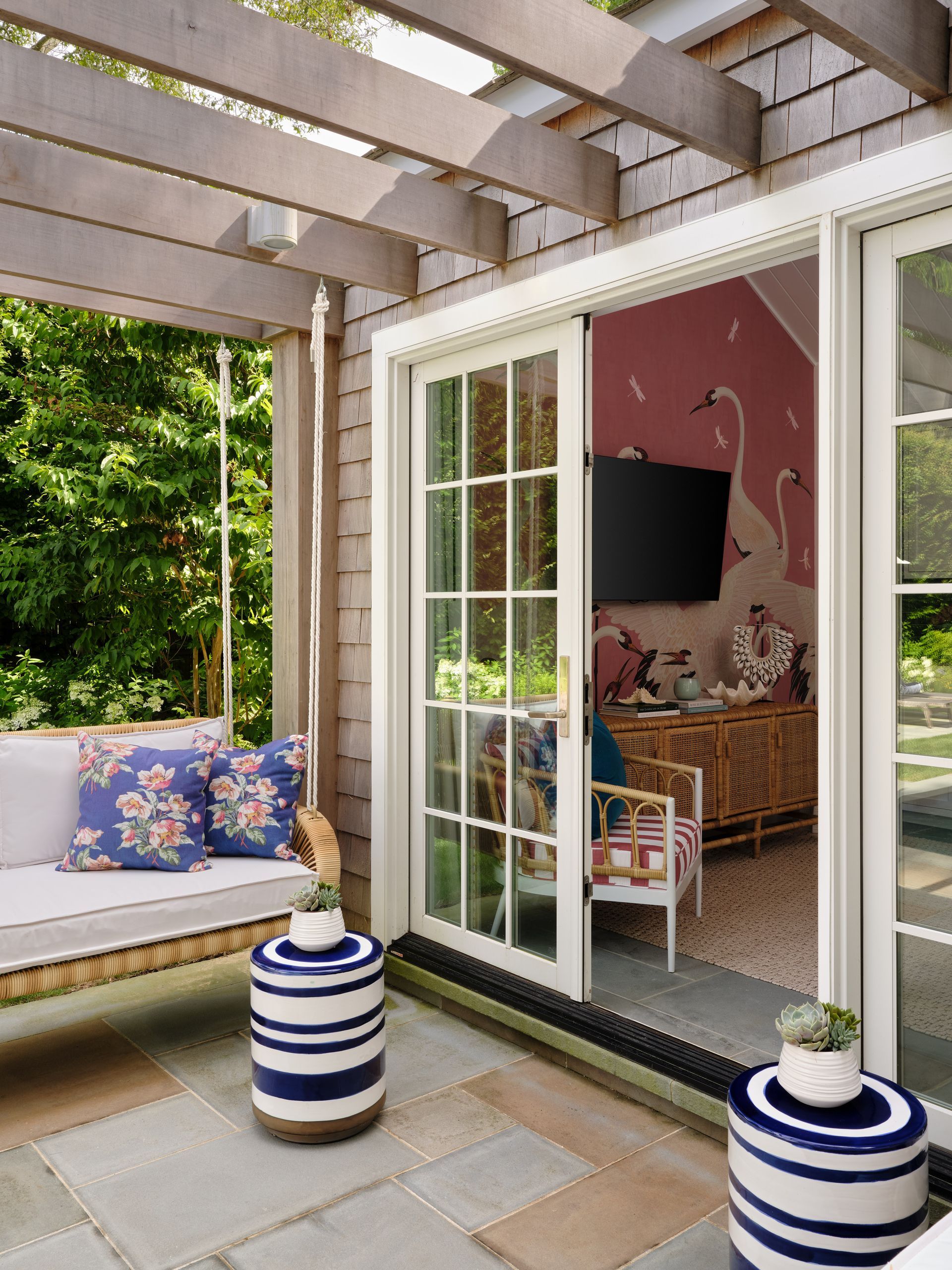 Patio with built-in bench, French doors, striped planters, and a view into a cozy pink room