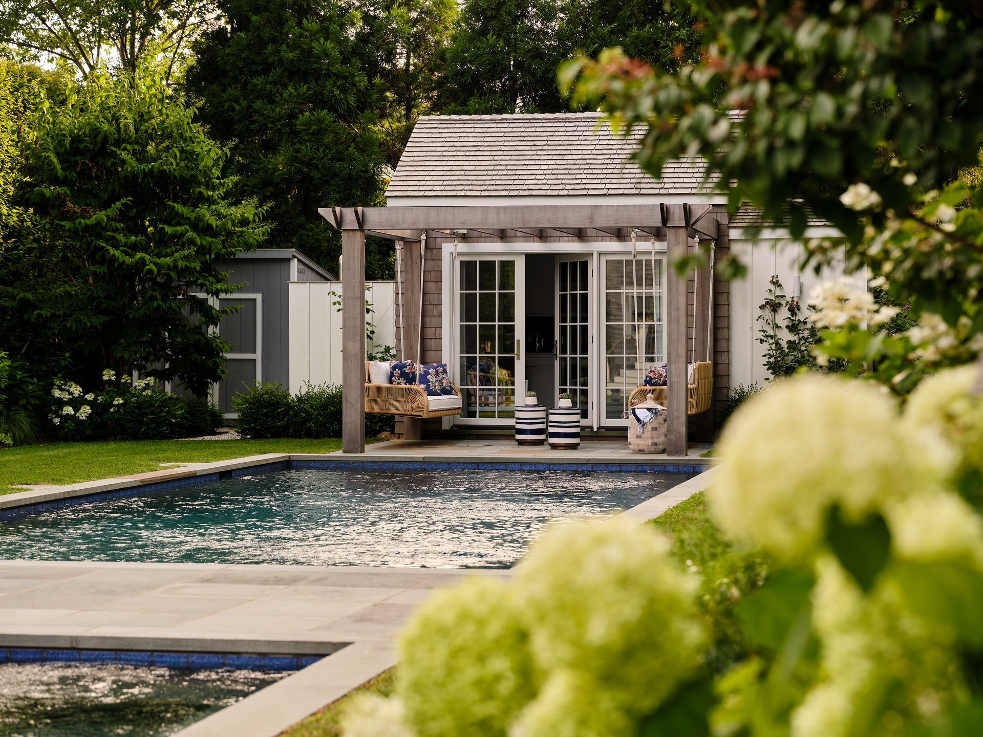 Backyard pool with a small gazebo and lush greenery in soft focus foreground