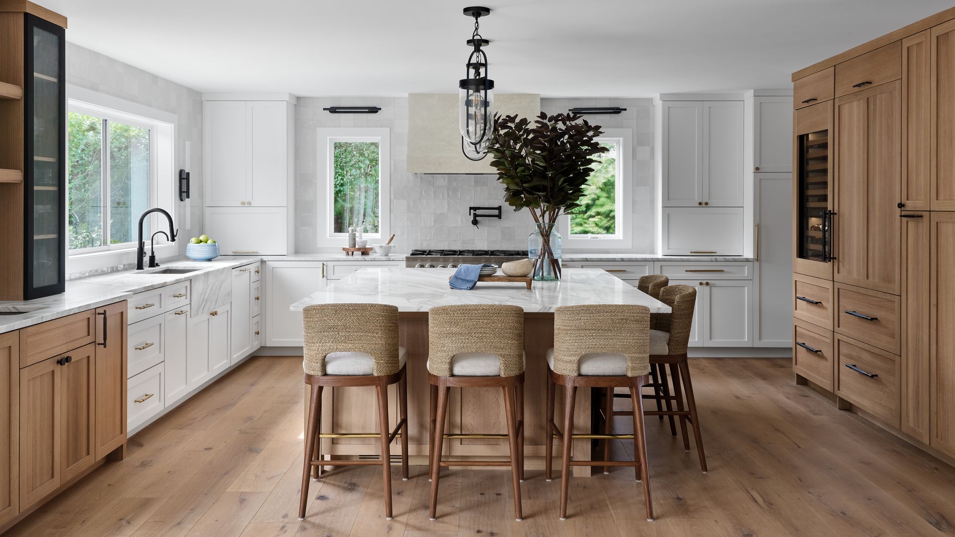 Bright modern kitchen with white cabinets, wood island, bar stools, and large pantry cabinet