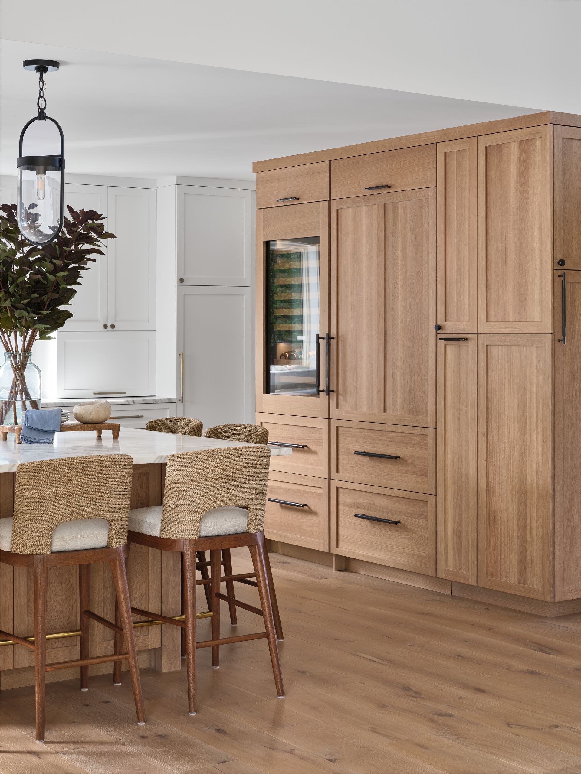 Modern kitchen with light wood cabinets, island seating, and a large built-in refrigerator.