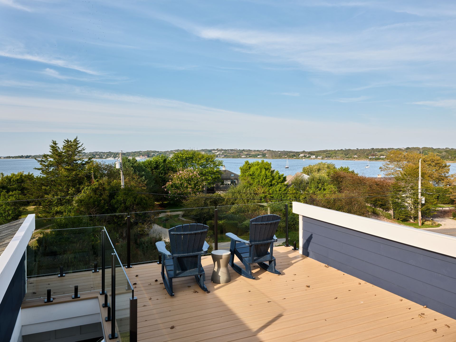Patio with two chairs overlooking trees, water, and a blue sky