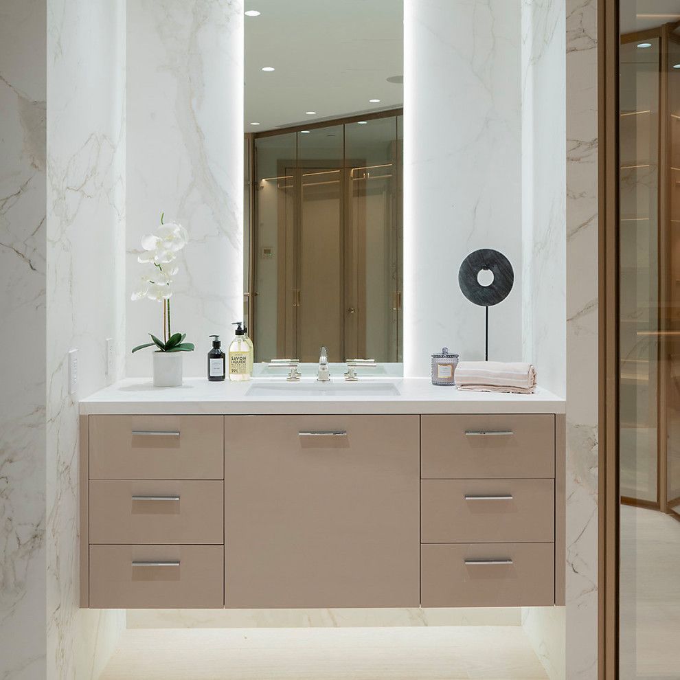 Modern bathroom vanity with beige cabinets, marble sink, large mirror, and glass shower doors