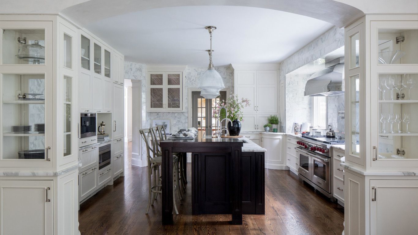 Bright white kitchen with dark island, hardwood floors, and cabinets on both sides