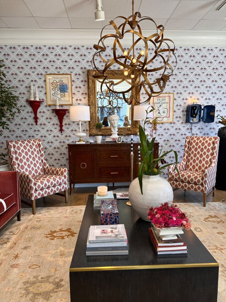 Boutique showroom with patterned chairs, dark desk, round table, and gold chandelier