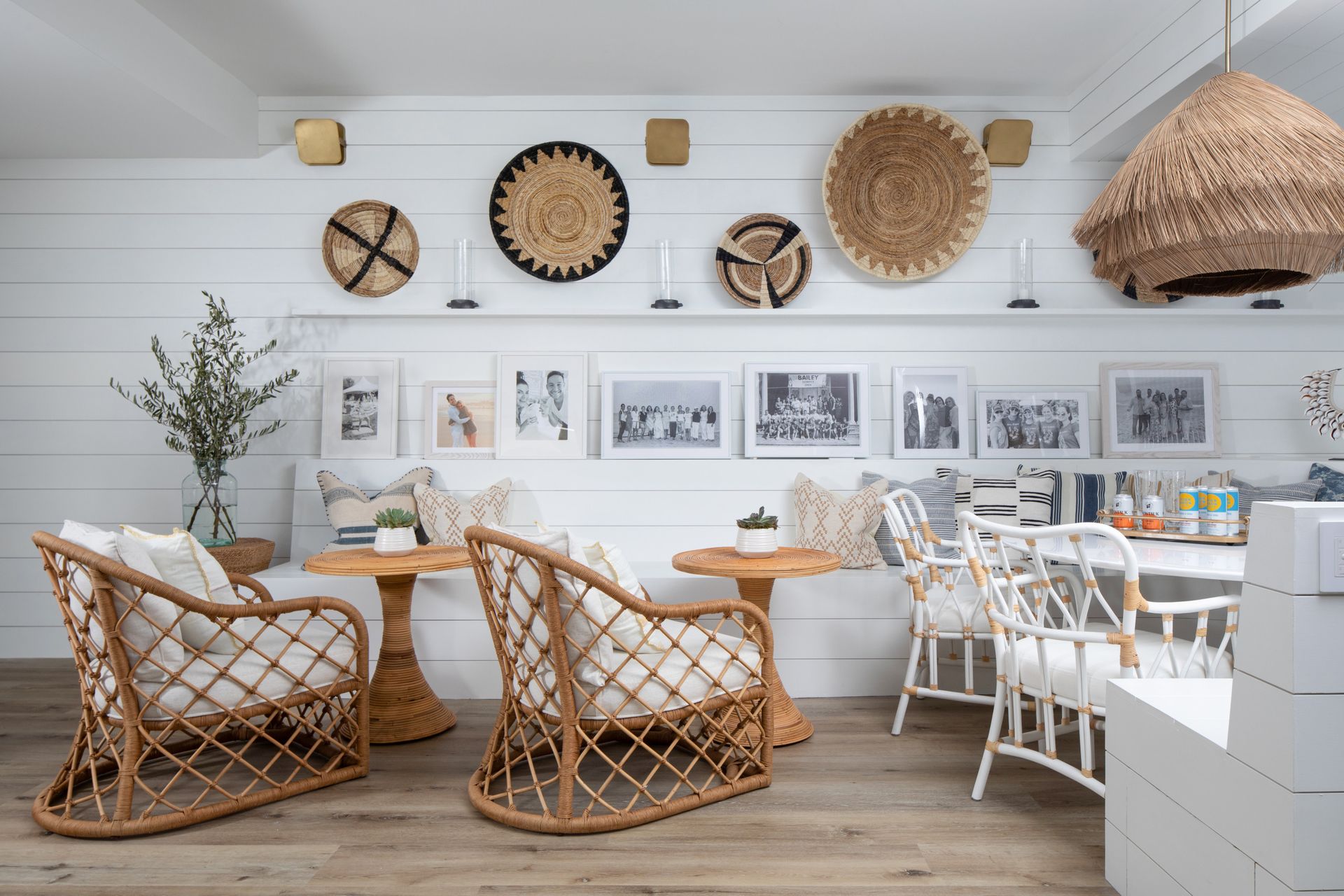 Bohemian-style living room with wicker chairs, white bench, framed wall art, and woven decor on a white wall