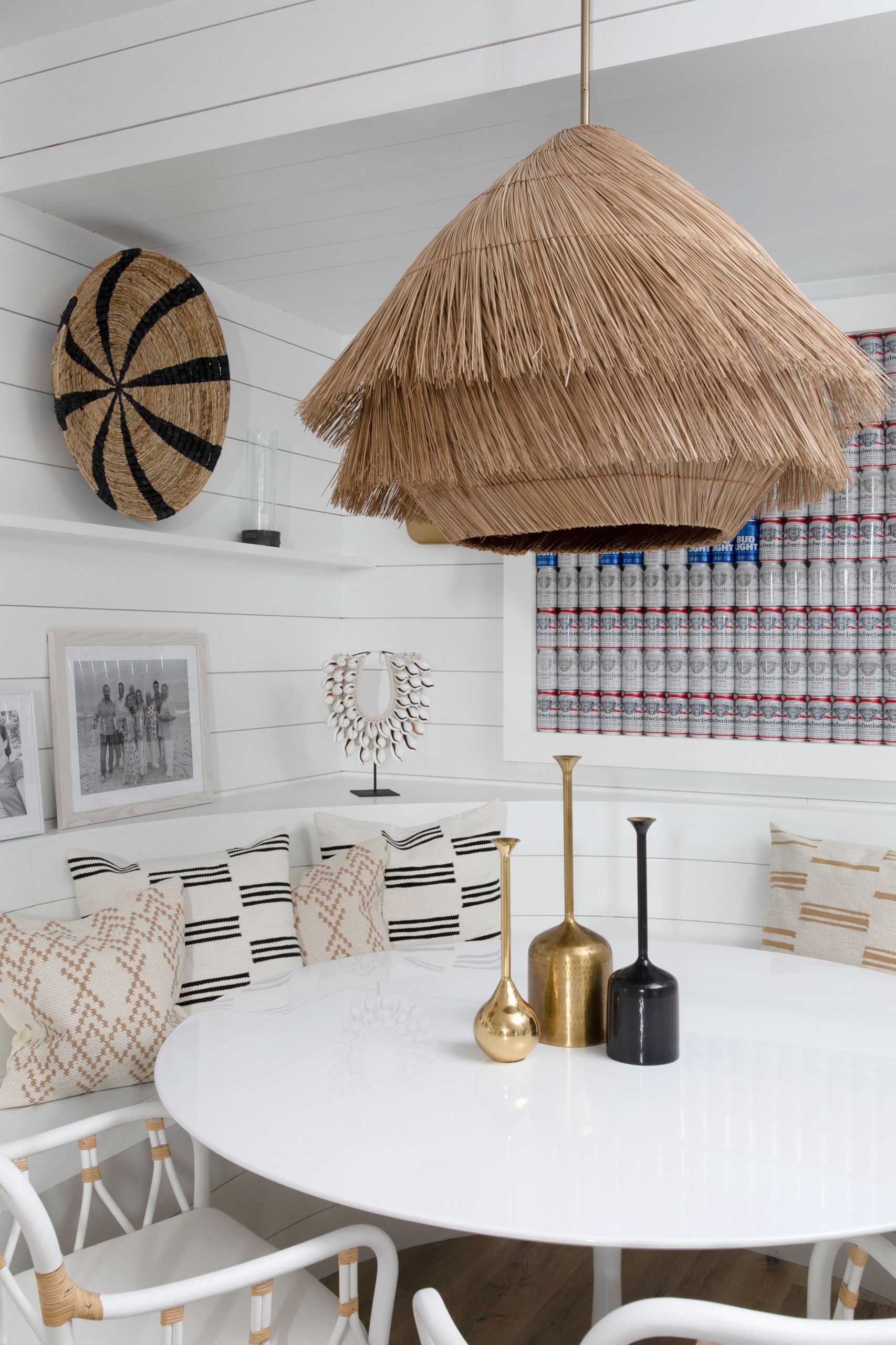 Cozy white dining nook with round table, woven pendant light, patterned cushions, and wall decor