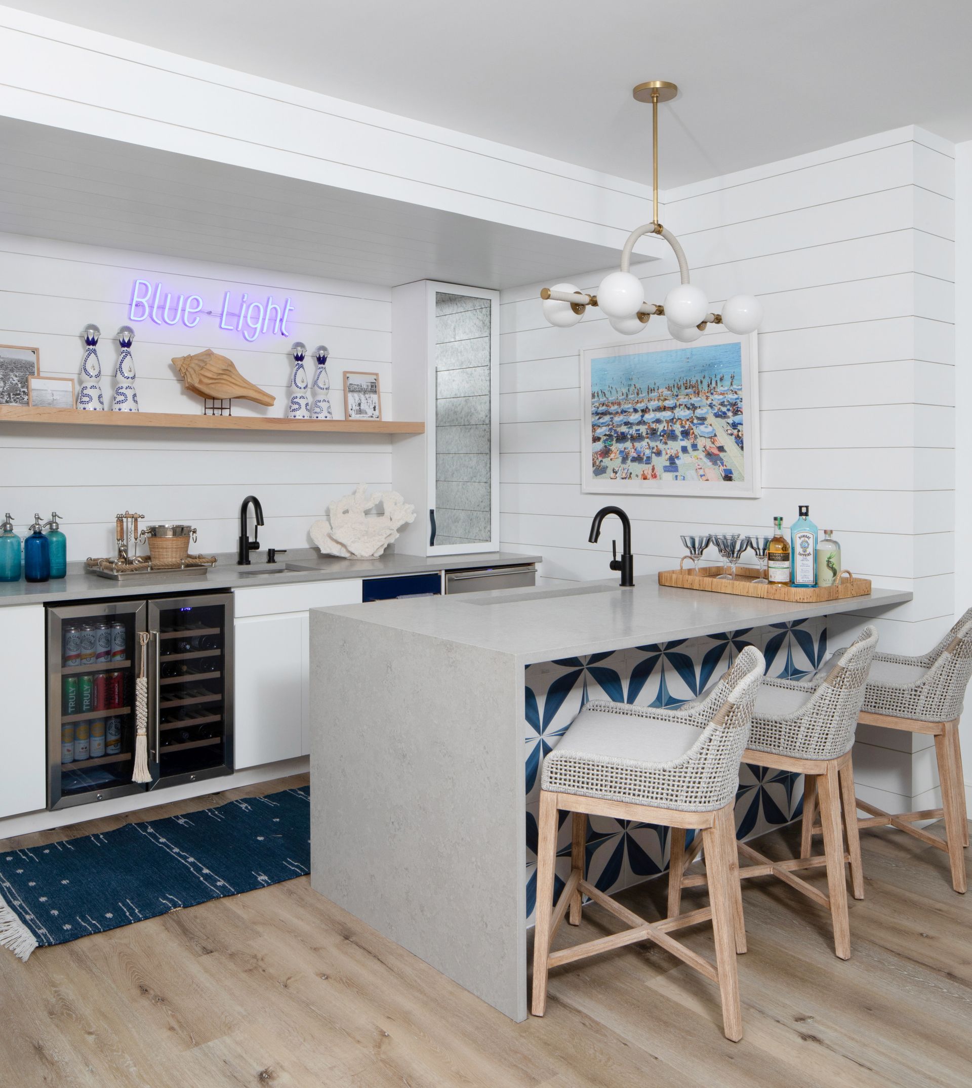 Bright modern kitchen with marble island, white walls, blue accents, and woven barstools