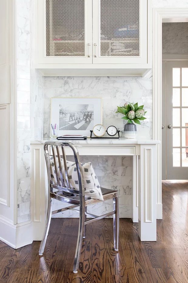 Bright home office nook with white desk, metal chair, flowers, and hardwood floor