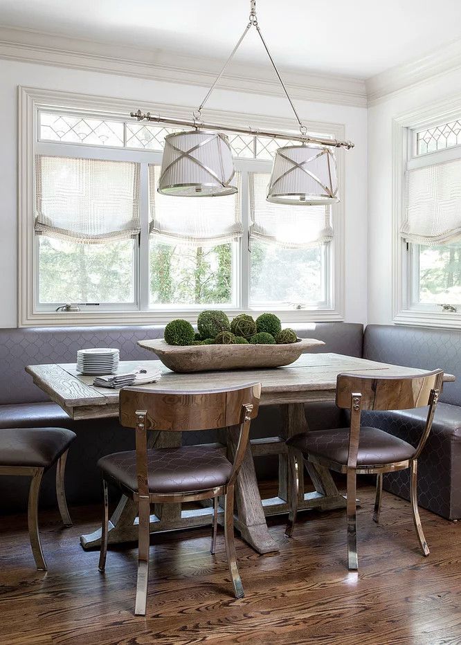 Bright dining room with a wooden table, mismatched chairs, large windows, and hanging pendant lights.