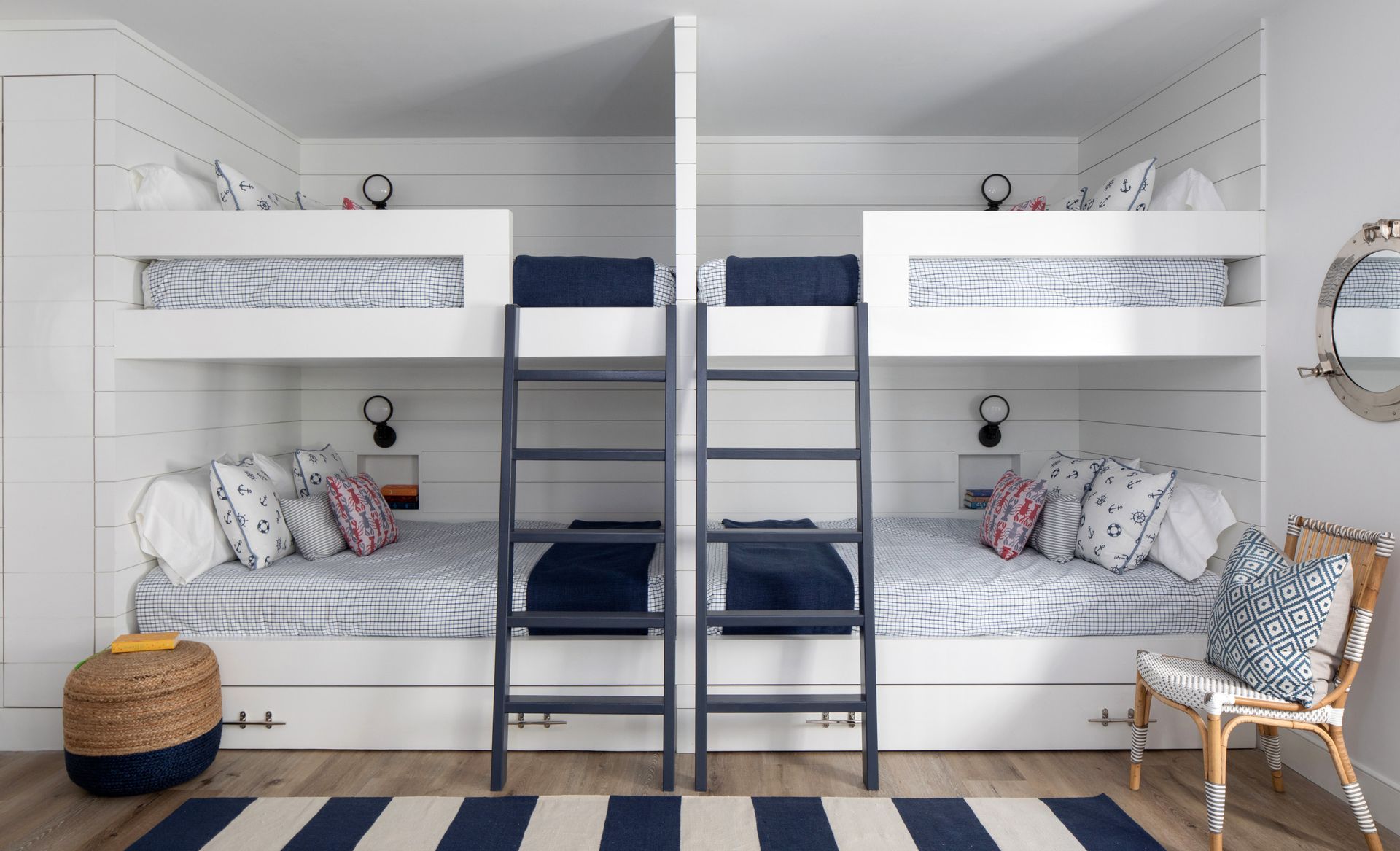 White bunk beds in a cozy, symmetrical bedroom with navy accents and patterned pillows