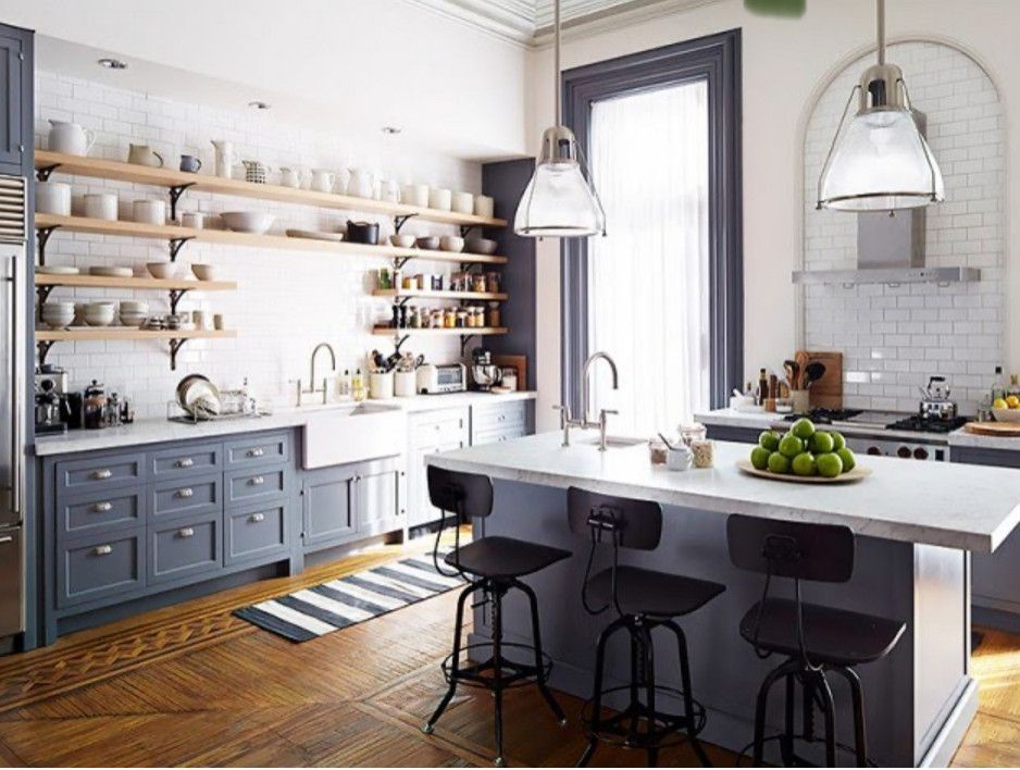 Bright modern kitchen with white cabinets, blue island, pendant lights, and fruit bowl on the counter